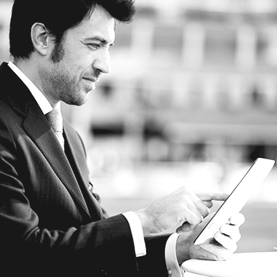 Homme d'affaire consultant les fonctionnalités de son compte VTC Transport Bretagne avec une tablette comme support.